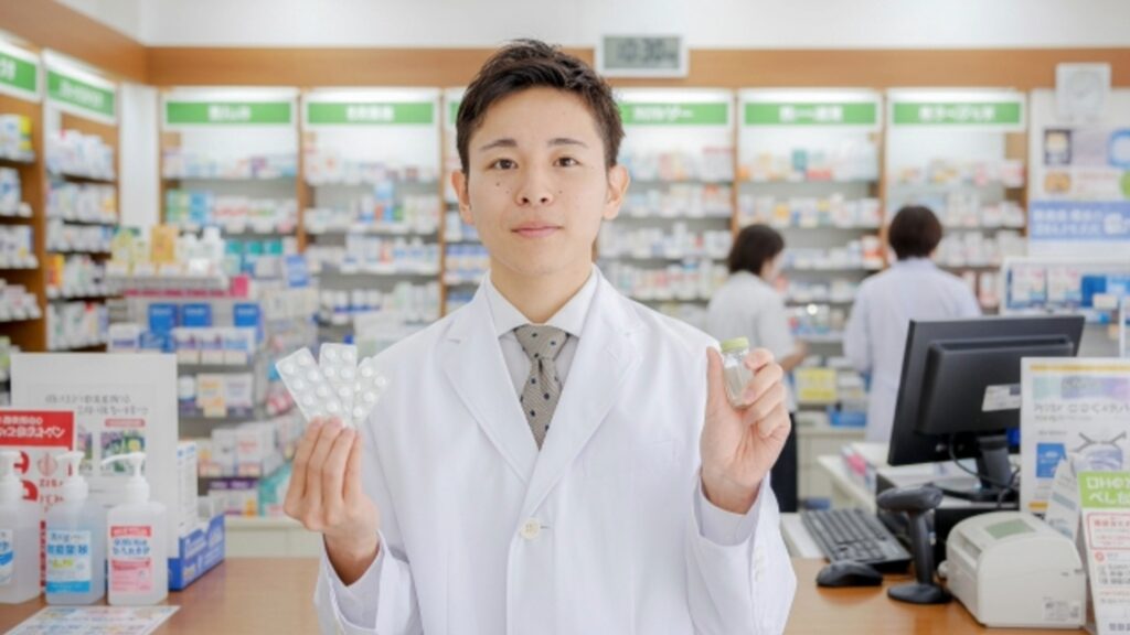 調剤薬局のカウンターで薬を手に持つ男性薬剤師。休みが取りやすく、働きやすい環境で充実した日々を送る薬剤師のイメージ。